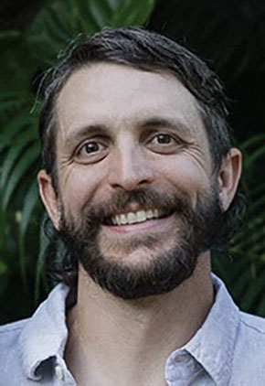 Dr. Weston Heintz smiles outside for a professional photo. He is wearing a light blue button-up.