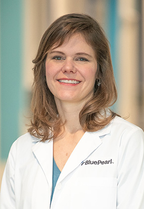 Dr. Christine Swanson smiling in the lobby of the Grand Rapids hospital. She has on her BluePearl white coat and a blue-green top.