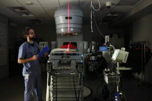 A vet technician monitors a cat undergoing radiation for a tumor.