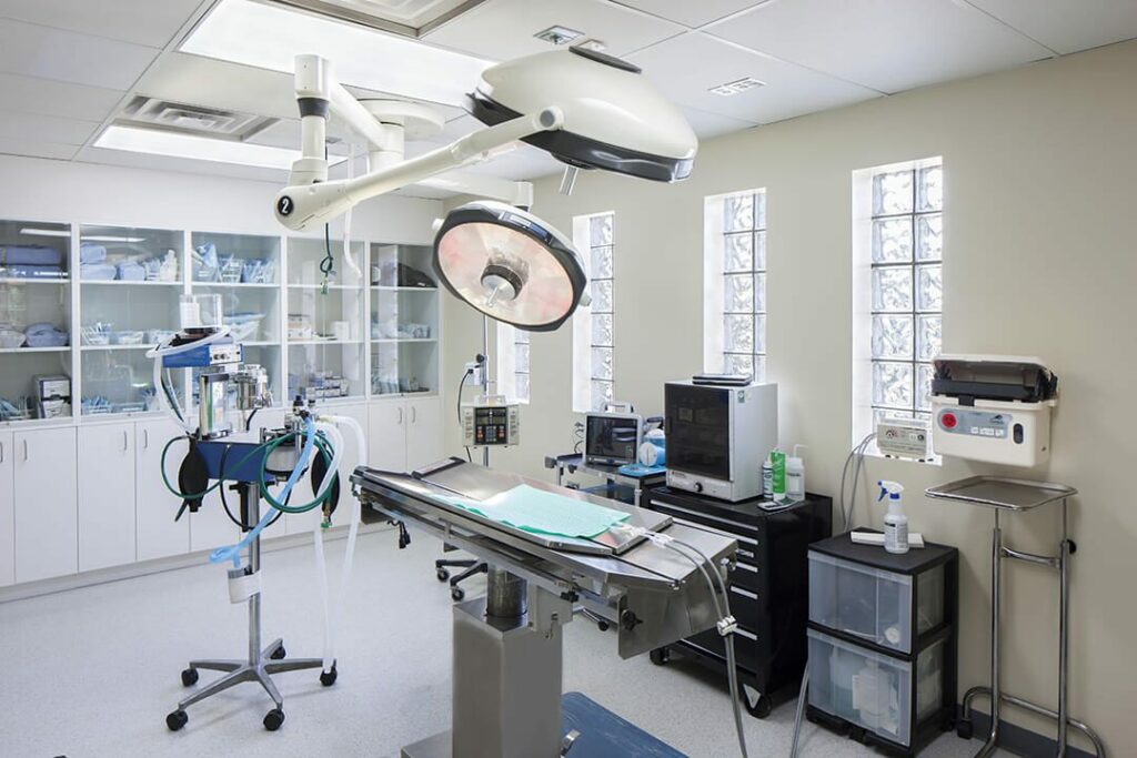 Surgical suite with a table and two large lights hanging from the ceiling.