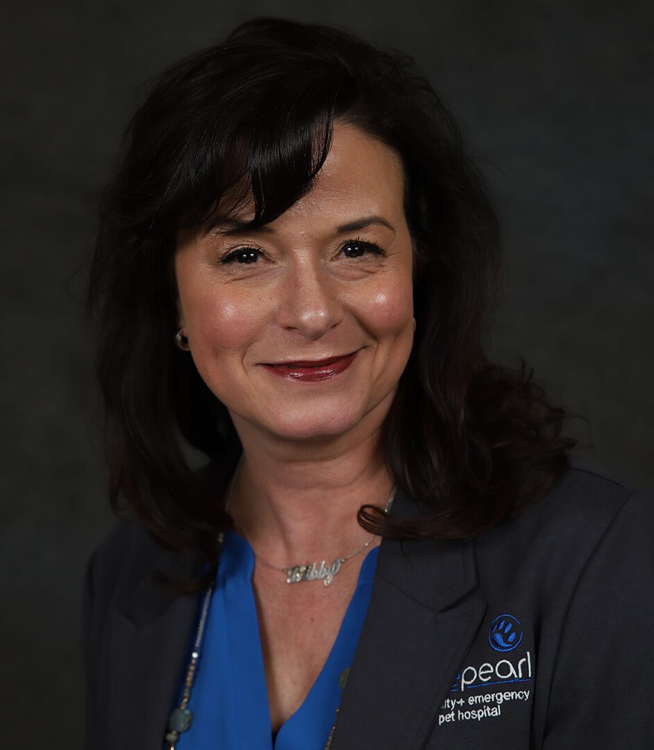 A woman with dark hair and eyes smiles.