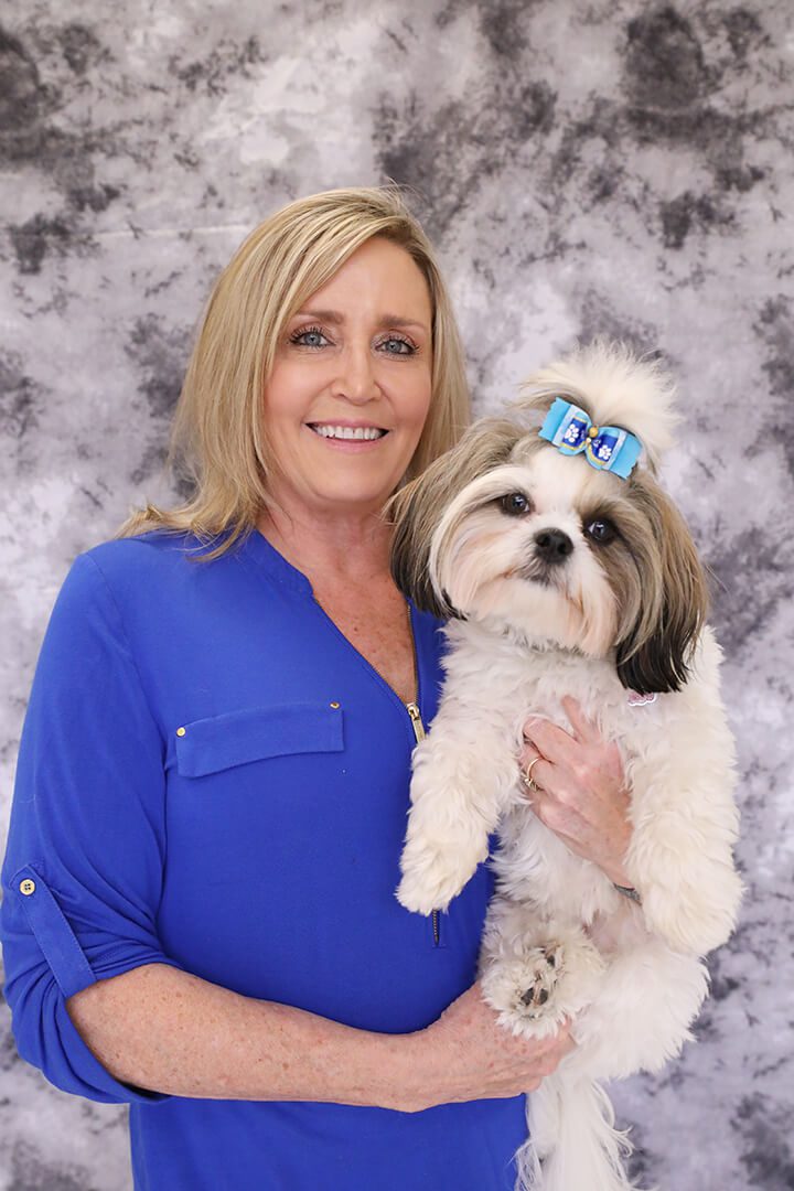 Blond woman with dark blue shirt on holds a fluffy white dog.