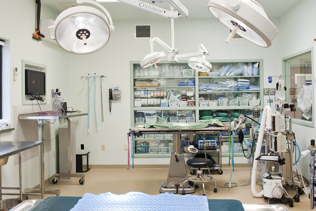 Surgical suite with two lights above a table and a cabinet with supplies in background.