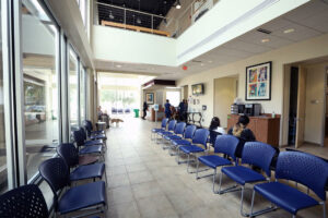 Lobby with two rows of blue chairs and windows to the front and left.