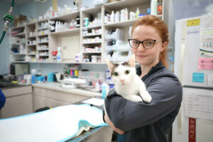 A BluePearl associate holds a cat in their arms while smiling.