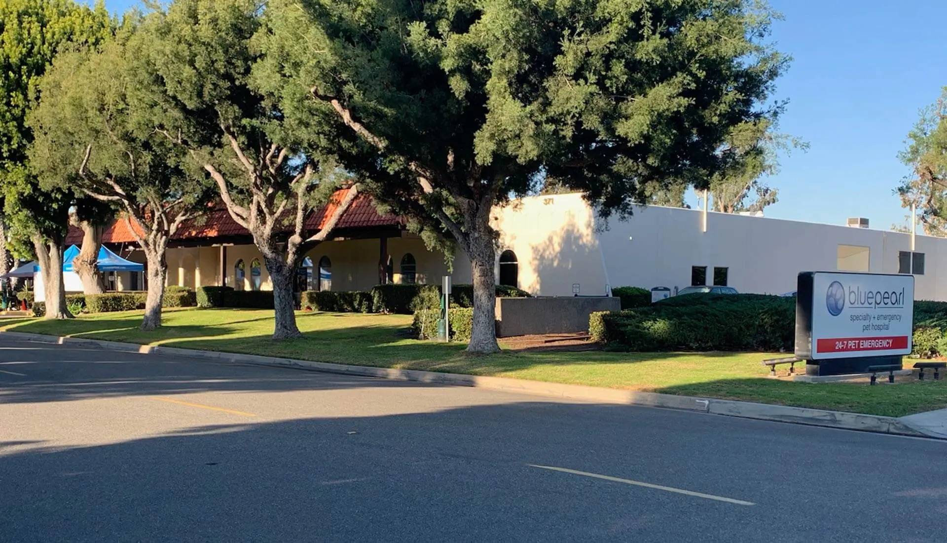 A tree lined road has a view of the hospital behind.