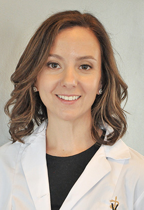 Dr. Margaret Gordon wearing a white veterinary coat over a black top, smiling in front of a neutral gray background.