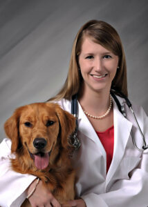 Female doctor with white coat with arm around dog. 