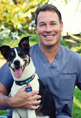 Dr. Travis Dennett is an emergency medicine clinician. He is holding a dog on his lap.