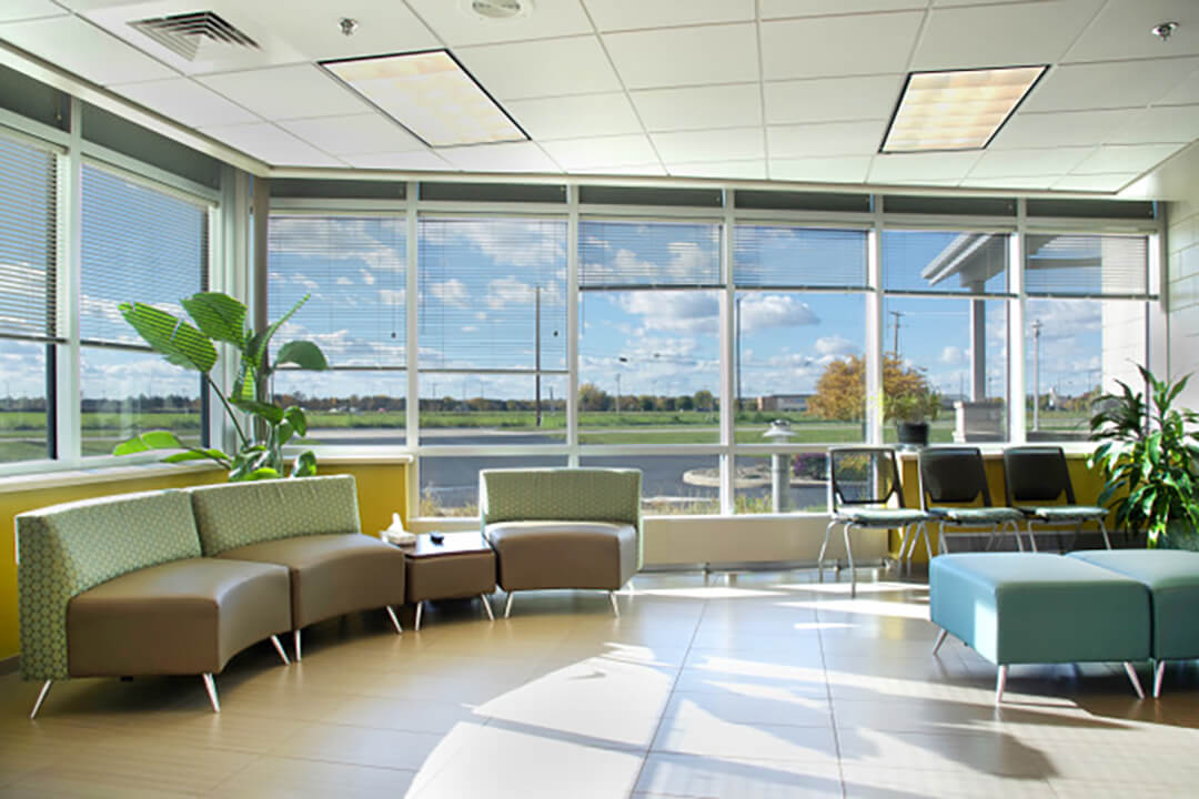 A bright spacious lobby is lined with windows and seating.