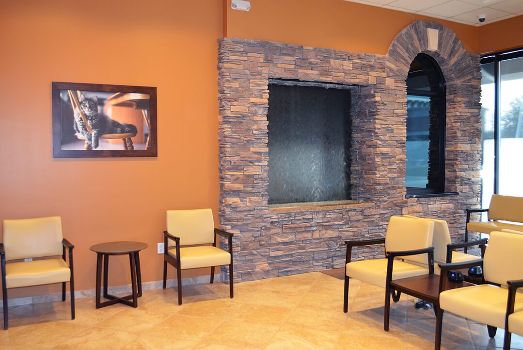 Waiting room with stone wall and tan chairs.
