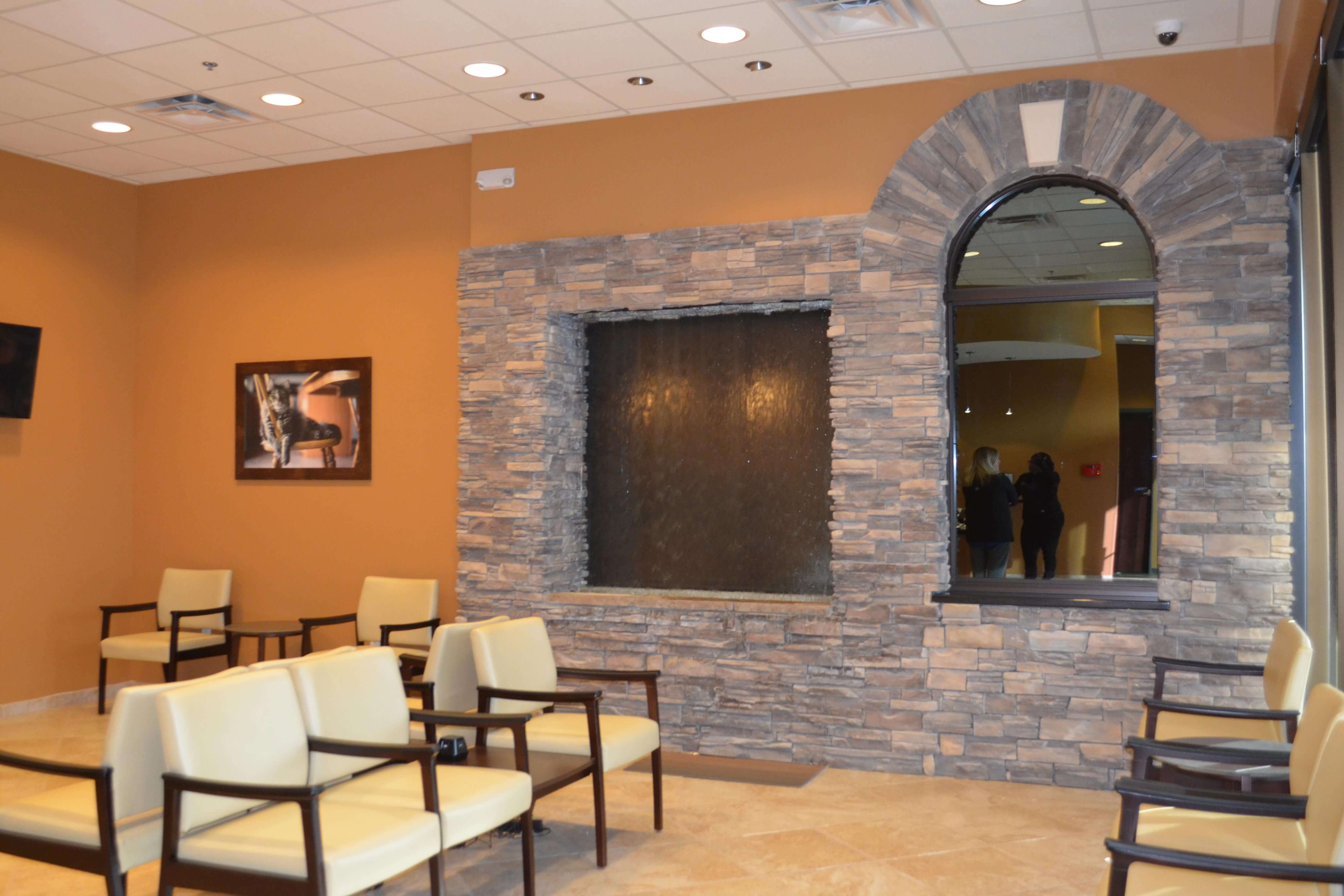 Lobby wall has warm tones with a large stonework window display. Seating in front.