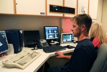 A vet and technician monitor computers with MRI scans.