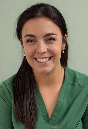 Dr. KP Spivey smiles in front of a light green background. She is wearing forest green scrubs.