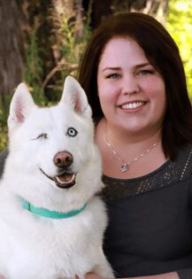 Dr. Rozemary Bal is an emergency medicine veterinarian. She is sitting next to a white dog.