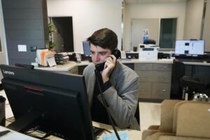 A man speaks to a client on the phone at the reception desk.