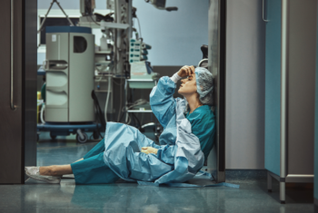 Doctor in PPE exhaustively sits on floor inside hospital
