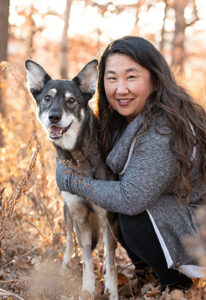 A woman in a grey sweater with a grey and white dog