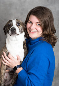 A woman in a royal blue sweater with a brown and white dog