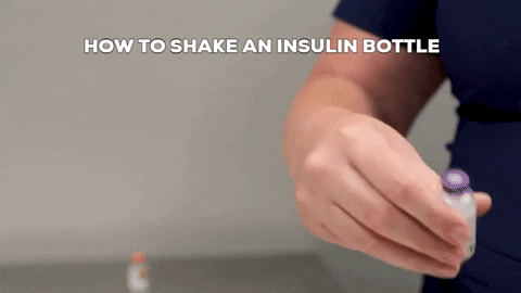 A vet tech shakes an insulin bottle.