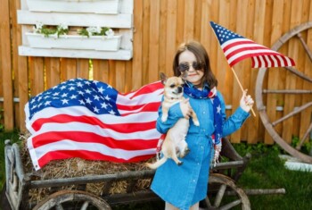 Young girl holds dog and American flag