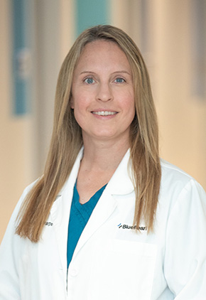 Dr. Maika Sharpe smiling in the lobby of the Grand Rapids hospital. She has on her BluePearl white coat and a teal top.