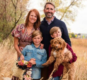 Family holds goldendoodle, Rosie, for family portrait. 