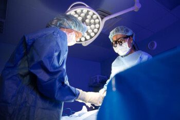 Dr. Leslie Thomas in a surgery, lit by an overhead light.