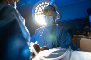 A veterinarian in scrubs performs surgery on a patient.