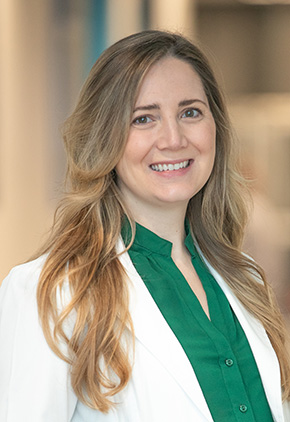 Dr. Alexandra Dunn smiling in the lobby of the Grand Rapids hospital. She has on her BluePearl white coat and a green top.