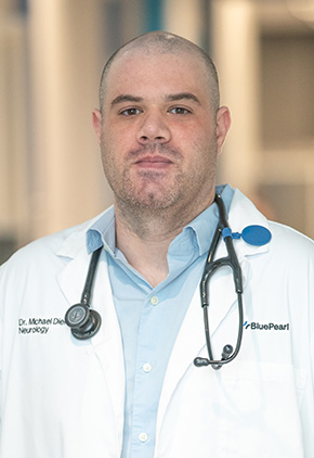 Dr. Michael Diehl in the front lobby of the Grand Rapids hospital. He has on his BluePearl white coat, a light blue button-up and a stethoscope around his neck.