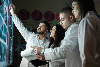 Veterinary students in lab coats examine x-rays with a veterinarian.