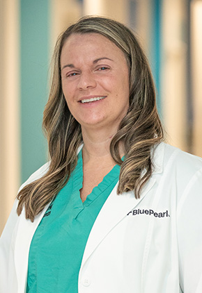 Dr. Elizabeth Brand smiling in the lobby of the Grand Rapids hospital. She has on her BluePearl white coat and a seafoam green top.