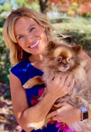 BluePearl Board Certified Cardiologist Dr. Andrea Eriksson smiling outside while holding her small dog.