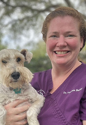 BluePearl Pet Hospice's Dr. Virginia Butler smiling, outside, holding her terrier/Schnauzer mix.