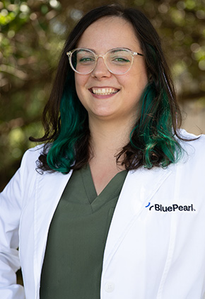 Dr. Jalisa Zimmerman smiling outside in her BluePearl white coat. She has on clear glasses and kelly green scrubs.