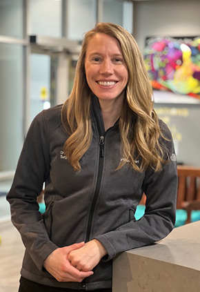 Dr. Kyla Walter smiling and leaning on the front desk of the Reno hospital. She has on a grey zip-up.