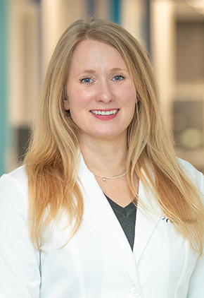 Dr. Genevieve Schildroth smiling in the lobby of the Grand Rapids hospital. She is wearing her BluePearl white coat and a grey top.