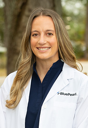 Dr. Kaylee Hass smiling outside in her white coat and a dark blue top.