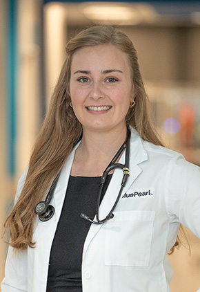 Dr. Amanda Rottman Torres smiling in the lobby of the Grand Rapids hospital. She has on her BluePearl white coat, a black top and a stethoscope around her neck.