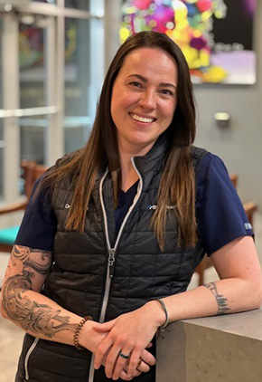 Dr. Caitlin Cosens smiling at the front desk in the Reno hospital. She has on a black BluePearl vest.