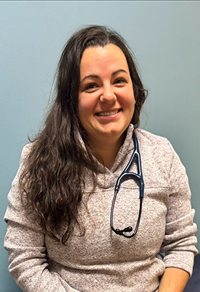 Dr. Lauren Young smiles for a headshot inside an exam room at our hospital. She is wearing a grey sweatshirt and has a stethoscope around her neck.