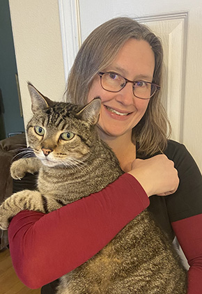 Dr. Loftin smiling while holding one of her brown, short-hair cats.