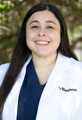 Dr. Ashley Cubb smiling outside. She has on her BluePearl white coat and a navy scrub top.