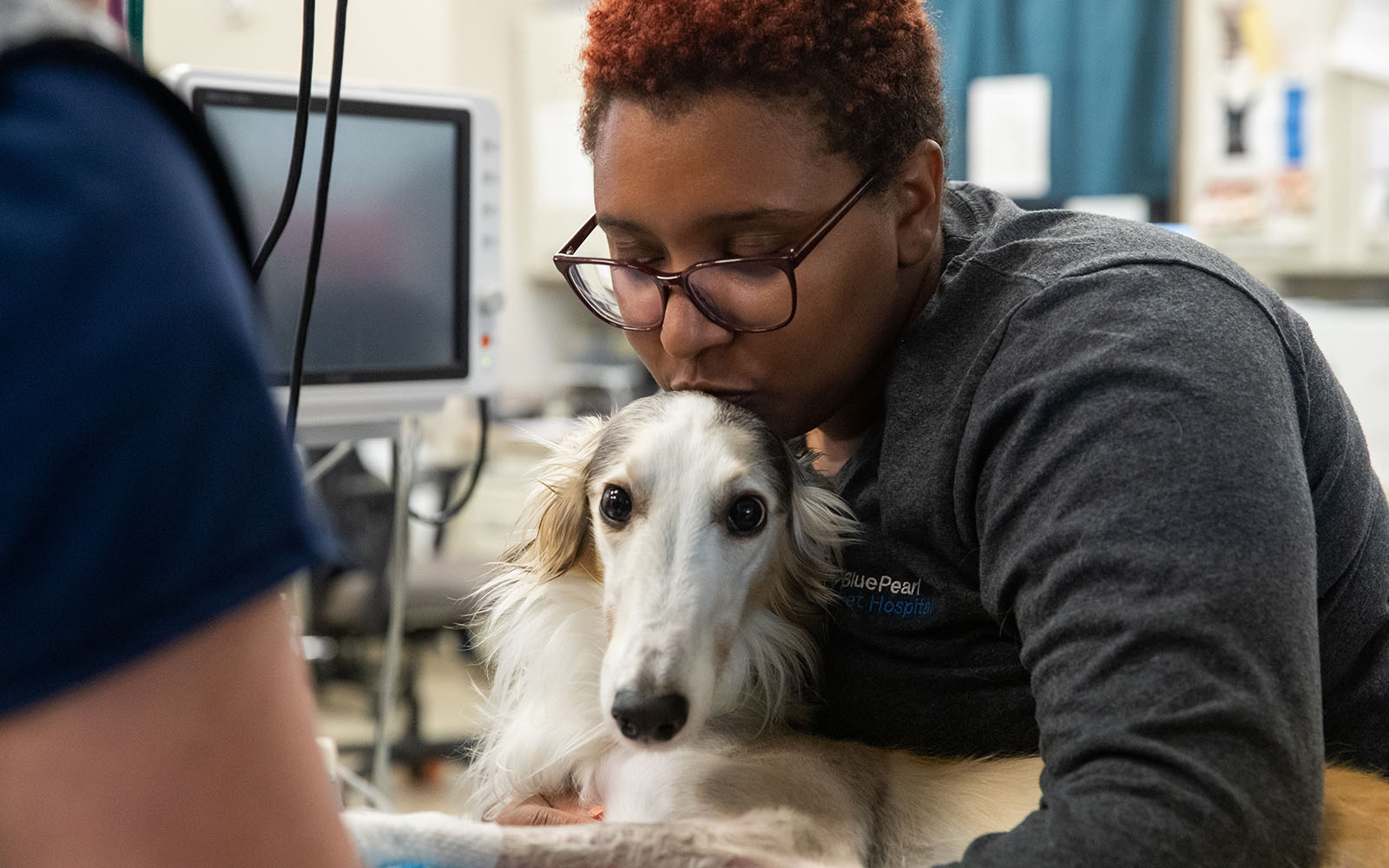 An Associate gives a kiss to a canine patient who is laying down.