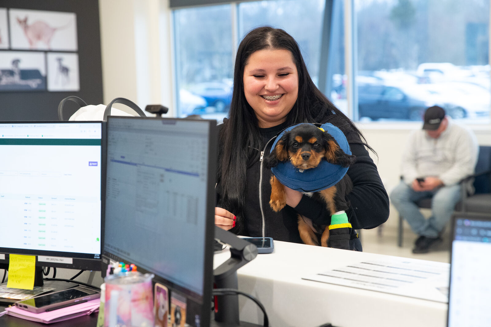 A BluePearl client smiles while holding her dog at the front desk of the animal hospital.