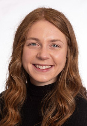 Dr. Breanna Dragseth smiling for a professional senior portrait in a black turtleneck in front of a white background.