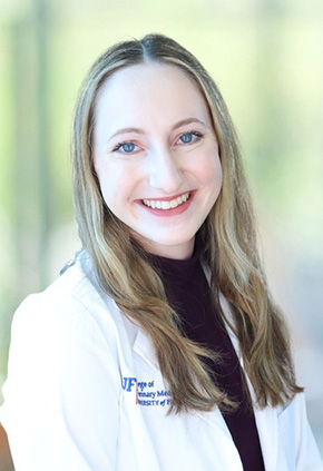 Dr. Emily Erdman smiling for a professional portrait. She is wearing a black top and her whitecoat.