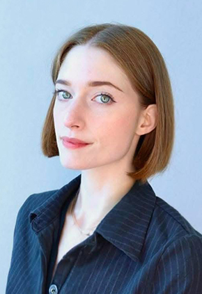 Dr. Camille Akin smiling in front of a white backdrop. She has on a black dress shirt with small grey pinstripes.