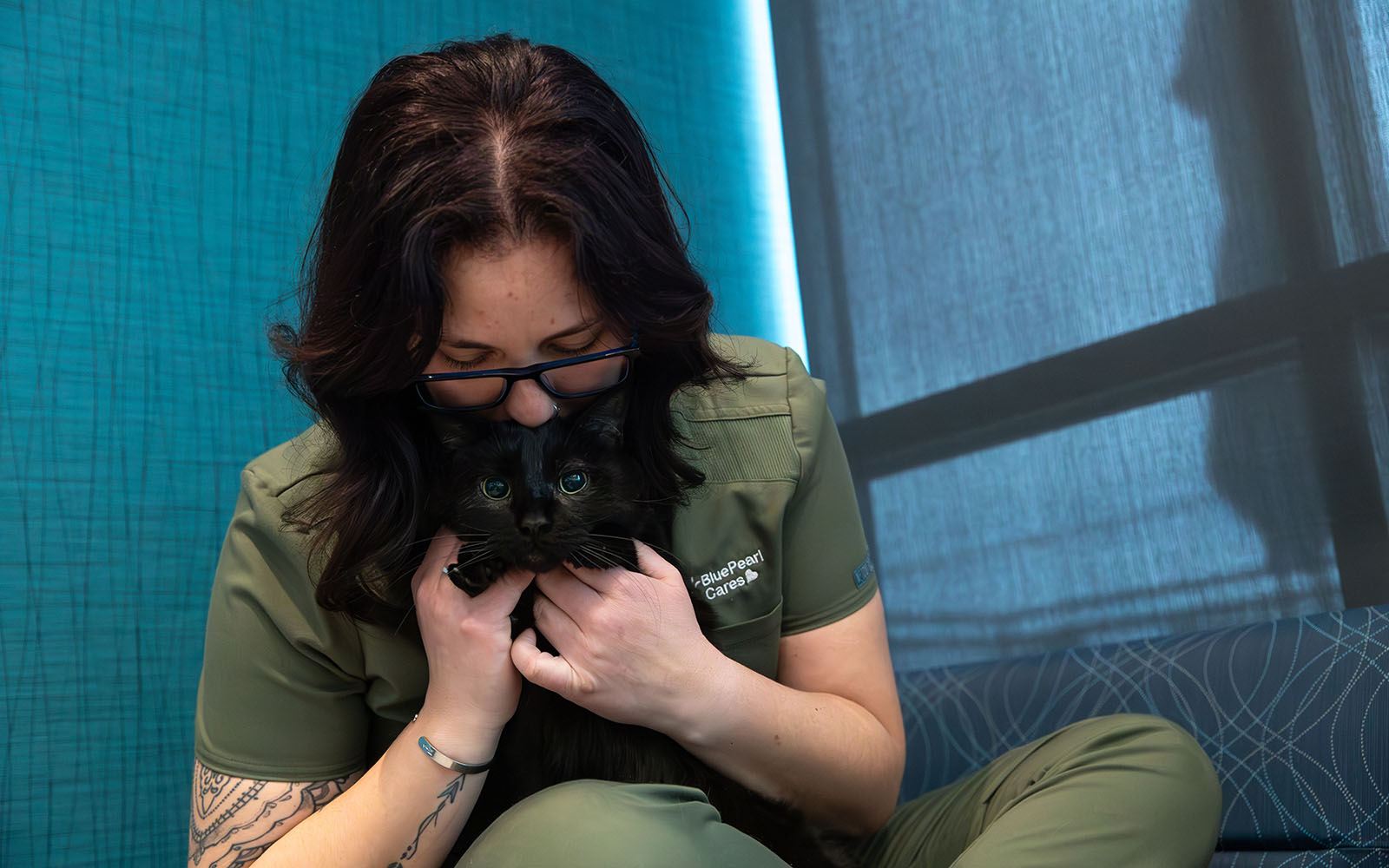 A blood bank technician snuggles a black cat